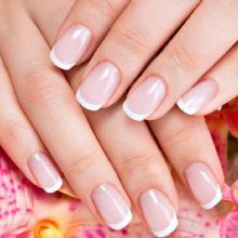Hands with French manicured nails over a floral background.
