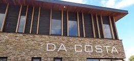 Het gebouw heeft een bakstenen gevel met grote letters "DA COSTA" erop.