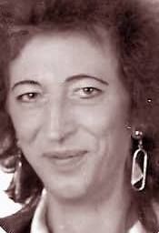 Schwarz-weiß Porträt einer lächelnden Frau mit lockigem Haar und Ohrringen.