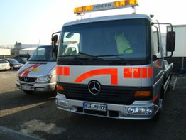 Zwei silberne Abschleppwagen mit roter Beschriftung im Freien geparkt.