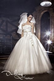 Braut in weißem Kleid mit Schleier steht in elegantem, rustikalem Raum.