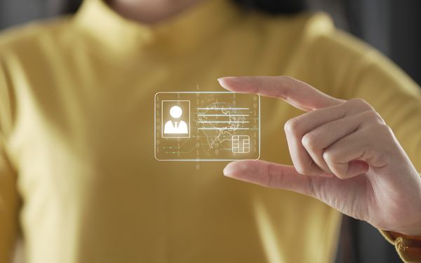 Eine Frau hält symbolisch eine Grafik einer digitalen ID-Card zwischen zwei Fingern.