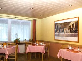 Gemütliches Café mit pinken Tischdecken und einem Gemälde an der Wand.