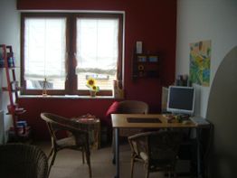 Gemütliches Büro mit zwei Stühlen, Tisch, Computer, Sonnenschirm-Gemälde und Sonnenblumen.