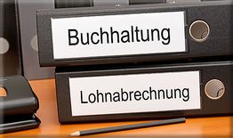 Ordner auf einem Tisch, beschriftet mit "Buchhaltung" und "Lohnabrechnung", daneben ein Bleistift.