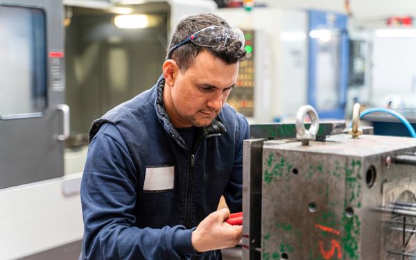 Arbeiter prüft Metallteil bei der Herstellung