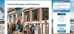 Menschen sitzen vor einem Ferienhaus auf Norderney, mit Hund und Fahrrädern, bei sonnigem Wetter.