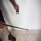 Person using a moisture meter on a white wall and a probe rod on tiled floor.
