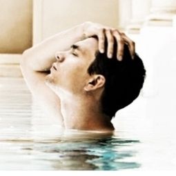 Mann entspannt im Wasser, hält den Kopf mit der Hand, Augen geschlossen.