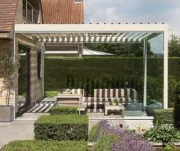 Moderne Terrasse mit Pergola, Sitzbereich und gepflegtem Garten.
