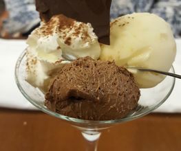 Postre en copa con helado de vainilla, chocolate, nata y decoración de chocolate oscuro.
