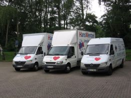 Drei Umzugswagen mit roten Herzen und der Aufschrift "Hans Wentzel" stehen nebeneinander geparkt.