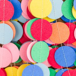 Colorful paper circles strung together, creating a festive decoration background.
