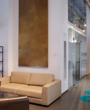 Ufficio moderno con divani beige, scaffali e corridoio con scritta blu a pavimento.