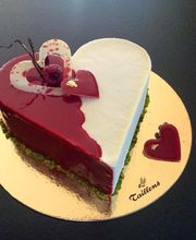 Herzförmige Torte mit rotem und weißem Überzug, verziert mit Himbeeren und Schokoladenherz.