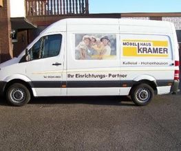 Lieferwagen mit der Aufschrift "Möbelhaus Kramer" und "Ihr Einrichtungs-Partner".