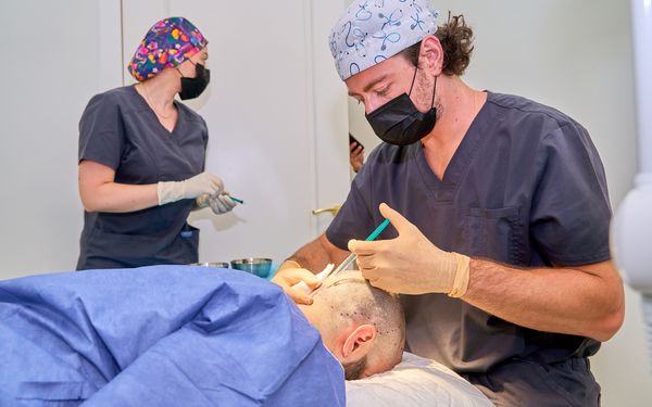Medizinisches Team führt bei einem Patienten eine Haartransplantation an der Kopfhaut durch.