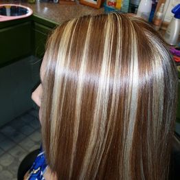 Hair with blonde and caramel highlights in a salon setting, viewed from the side.