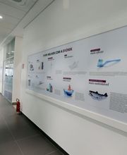 Corredor de escritório com um quadro informativo na parede, refletindo luz suave.