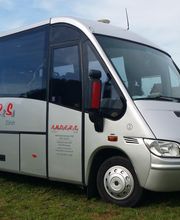 Silberner Minibus mit Aufschrift "A.N.D.E.R.S" auf grüner Wiese bei blauem Himmel.