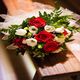 Bouquet of red and white roses with greenery on a wooden bench.