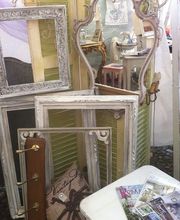 Antike Spiegel und Bilderrahmen aus Holz auf einem Flohmarkt, mit Zeitschriften auf einem Tisch.