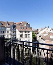 Blick von einem Balkon auf alte europäische Gebäude unter blauem Himmel.