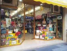 Escaparate de tienda con bolsos y maletas coloridos, vista desde la calle.