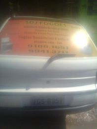 Carro branco com adesivo de publicidade da SDJ Fogões no vidro traseiro.