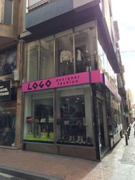 Tienda de moda de diseñador con fachada de vidrio y letrero rosa "LOGO".