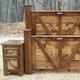 Wooden bed with rustic headboard and a matching bedside table in a forest setting.