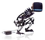 Roboterfigur aus Metall mit Fernseher als Kopf und angeschlossenem Kabel auf weißem Hintergrund.