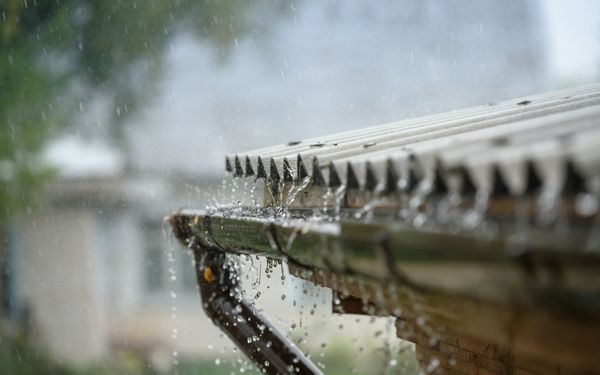 Verstopfte Dachrinne läuft bei Regen über.