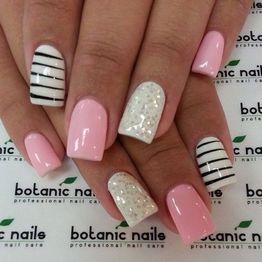 Unghie con smalto rosa, bianco con glitter e righe nere su sfondo botanic nails.