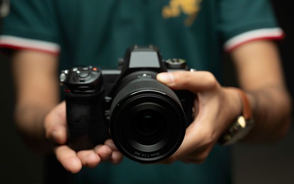 Mann in grünen Poloshirt hält Kamera in der Hand.