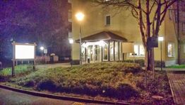 Gebäude bei Nacht mit Laterne, Schildern und Bäumen, beleuchtet von Straßenlaterne.