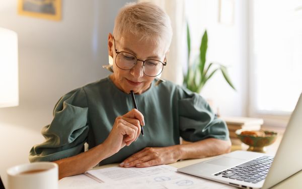 Eine ältere Dame füllt Anträge für Zuschüsse für die Gestaltung eines barrierefreien Bads aus.