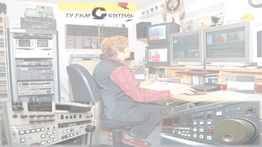 Person in einem Fernsehstudio vor mehreren Monitoren und technischen Geräten sitzend.
