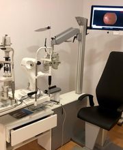 Consultorio de oftalmología con maquinaria y pantalla mostrando imagen ocular.