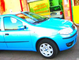 Auto blu parcheggiata davanti a un edificio dai colori vivaci.
