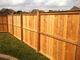 Wooden fence along a grassy area under a cloudy sky.