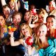Group of smiling friends raising colorful drinks at a party.