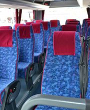 Innenraum eines leeren Busses mit blauen Sitzen und roten Kopfstützen in mehreren Reihen.