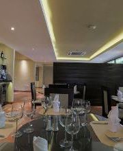 Restaurante elegante con mesas preparadas, bar al fondo y ventanales a la derecha.