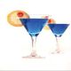 Zwei blaue Cocktails in Martini-Gläsern mit Zitronenscheiben und Kirsche garniert.