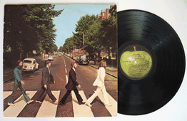 Een lp-hoes van een band die over een zebrapad loopt, naast een zwarte vinylplaat.