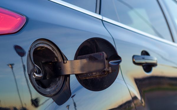 Ein offener Tankdeckel an einem schwarzen Auto.