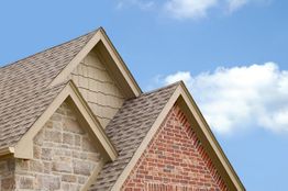 Roof peaks with different textures against a blue sky.