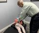 Man adjusting child's back on a chiropractic table in a clinic room.