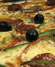 Pizza mit schwarzen Oliven, Paprika, Wurst und geschmolzenem Käse.